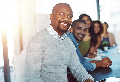 Buy stock photo Portrait of a businessman sitting in a boardroom with his colleagues blurred out in the background