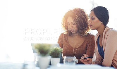 Buy stock photo Shot of two young coworkers using a laptop together at work