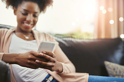 Buy stock photo Shot of an attractive young woman using her cellphpone while chilling at home on the sofa