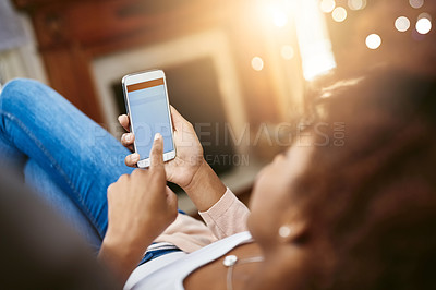 Buy stock photo High angle shot of an unrecognizable young woman using her cellphpone while chilling at home on the sofa