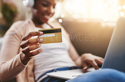 Buy stock photo Shot of an unrecognizable young woman shopping online while chilling at home on the sofa