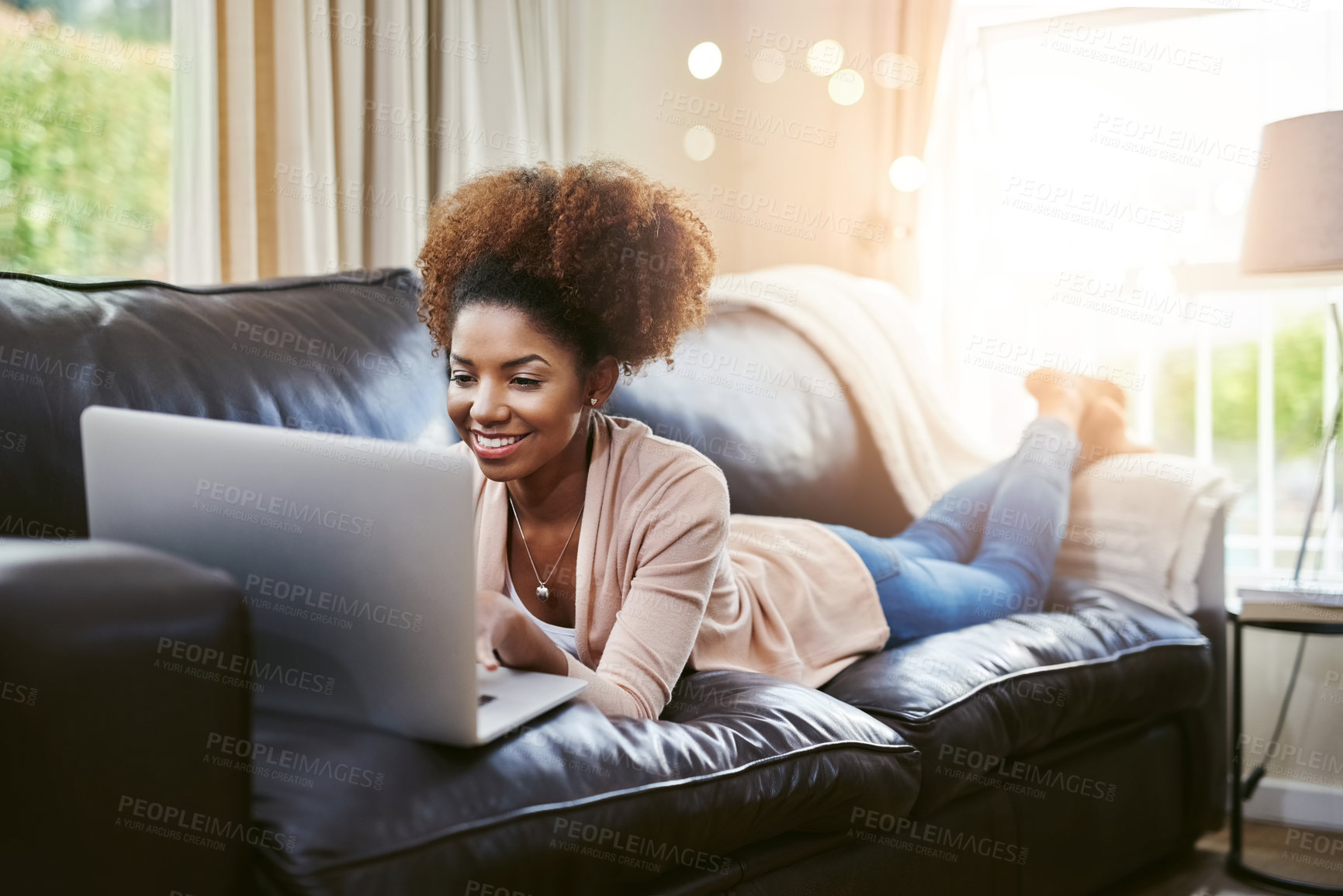 Buy stock photo Shot of an attractive young woman using laptop while chilling at home on the sofa