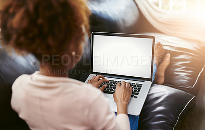 Buy stock photo High angle shot of an unrecognizable young woman using her laptop while chilling at home on the sofa