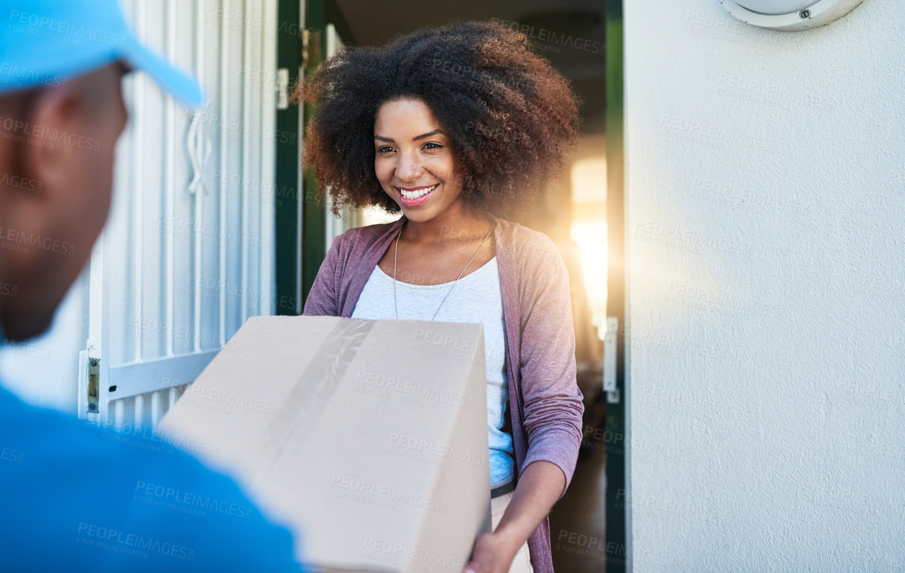 Buy stock photo Shot of a postal worker delivering a package to a young female customer