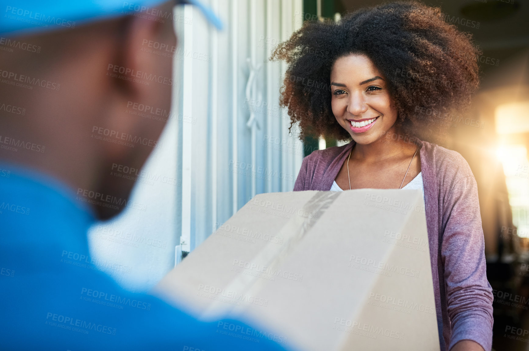 Buy stock photo Shot of a postal worker delivering a package to a young female customer