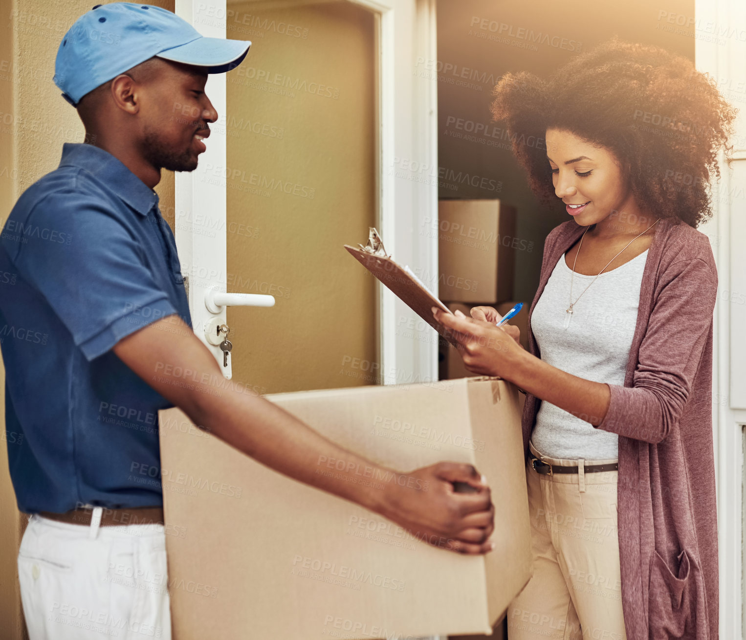 Buy stock photo African delivery man, woman and signature for box, stock and import documentation at front door. People, courier and writing with invoice, clipboard and package for e commerce services at apartment