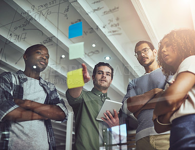 Buy stock photo Low angle shot of a group of young designers planning on a glass board