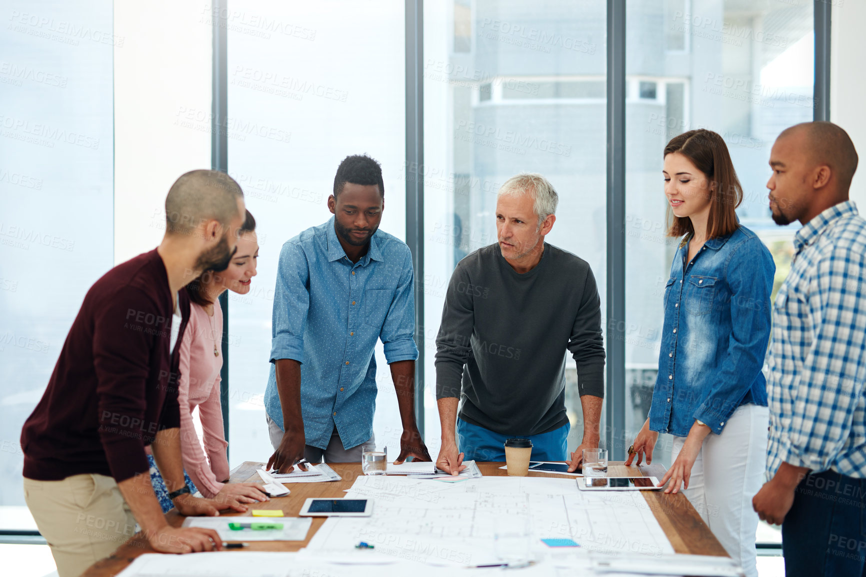 Buy stock photo Cropped shot of a group of architects working on blueprints in the boardroom