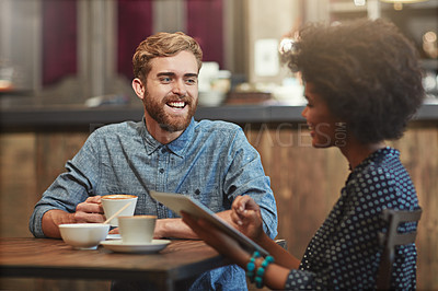 Buy stock photo Shot of a young couple using a digital tablet together on a coffee date