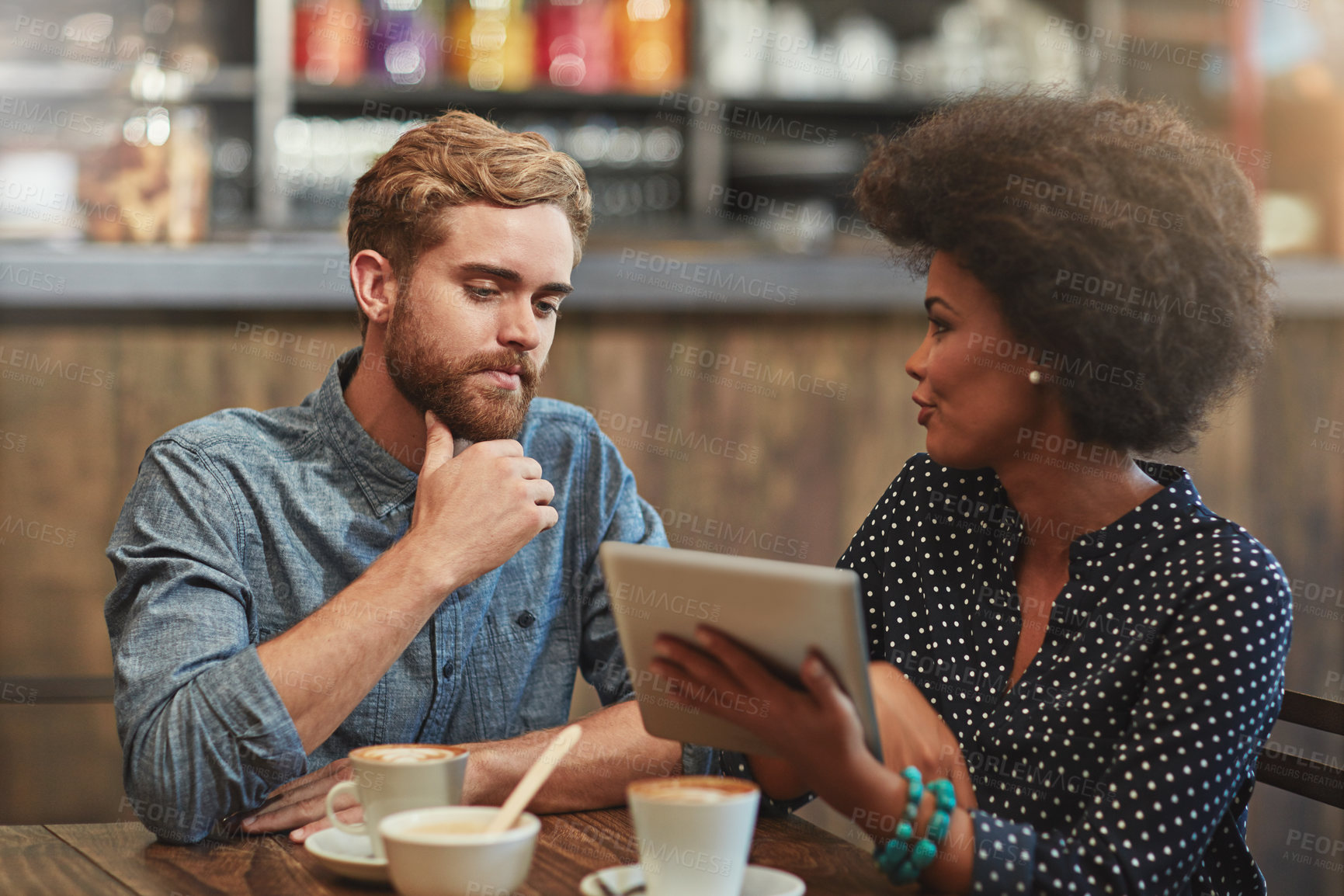 Buy stock photo Couple, tablet and online with discussion in cafe for restaurant reviews, digital menu or article. Interracial, people and talking in coffee shop with tech app for web browsing, conversation or relax