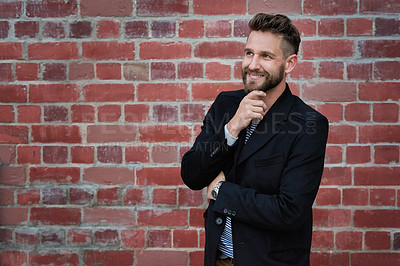 Buy stock photo Thinking, happy and education with a man planning on college campus alone against a brick wall background. Idea, smile and study with a young male pupil standing inside at university for learning