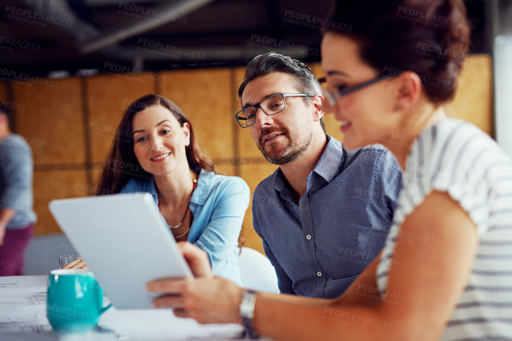 Buy stock photo Shot of a group of designers using a digital tablet in their meeting