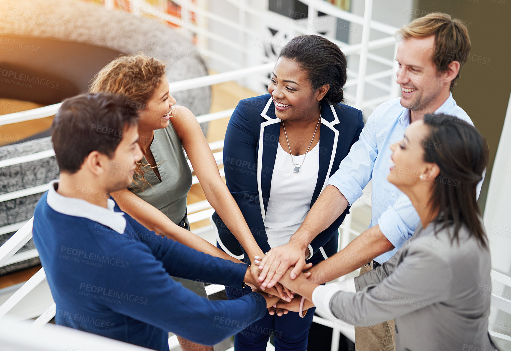Buy stock photo Shot of a group of coworkers standing with their hands together in a huddle in an office