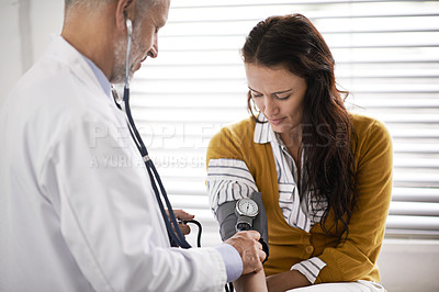 Buy stock photo Cropped shot of a doctor checking a patient's blood pressure