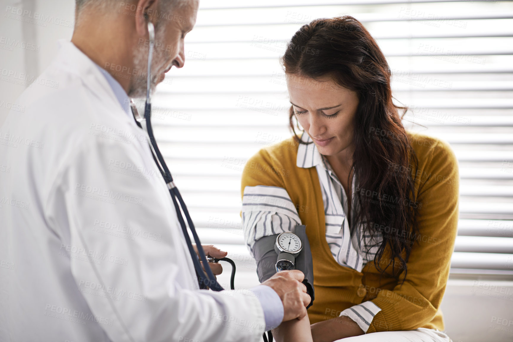 Buy stock photo Cropped shot of a doctor checking a patient's blood pressure
