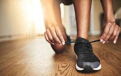 Buy stock photo Cropped shot of a young woman tying her shoelaces