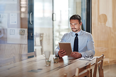 Buy stock photo Shot of a businessman using a digital tablet in an office