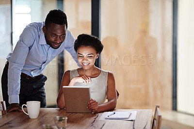Buy stock photo Shot of two colleagues using a digital tablet together in an office