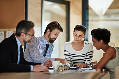 Buy stock photo Shot of a group of colleagues using a digital tablet together while working around a table in an office