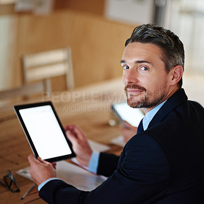Buy stock photo Portrait of an executive using a digital tablet while sitting alone at a table in an office