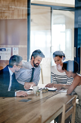 Buy stock photo Shot of a group of colleagues using a digital tablet together while working around a table in an office