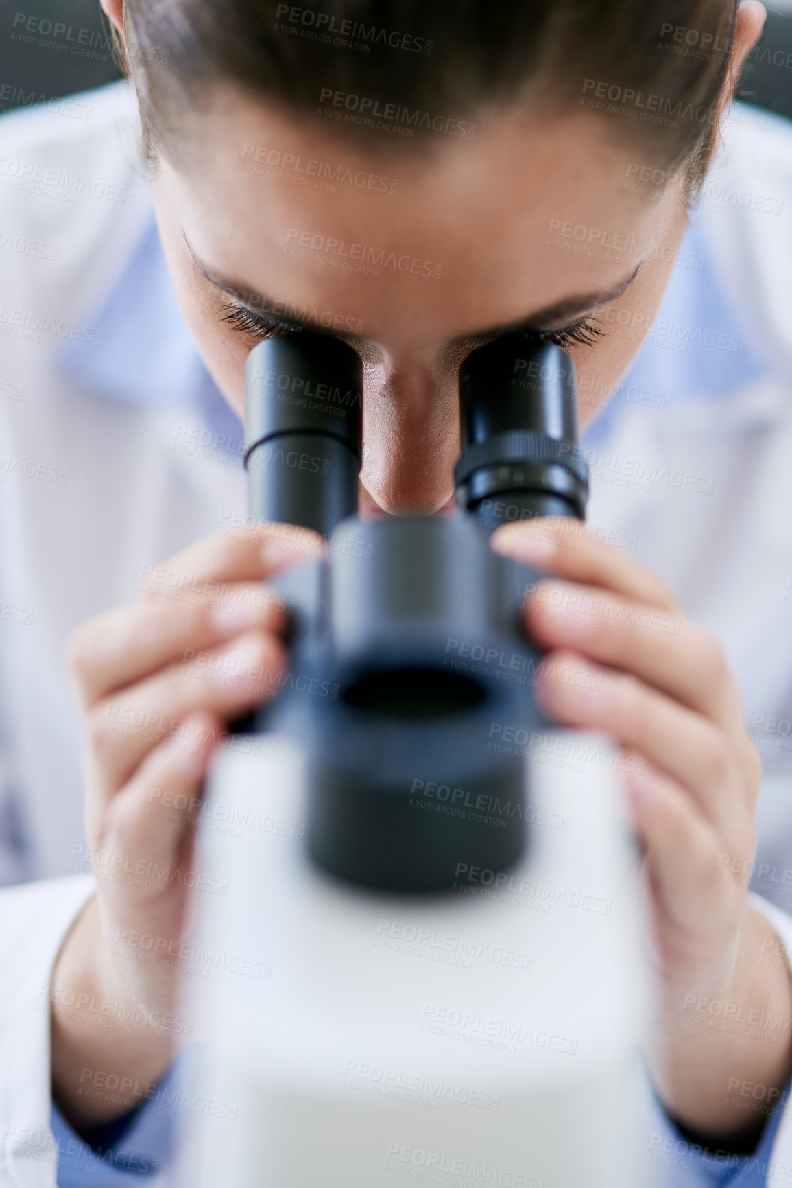 Buy stock photo Cropped shot of a young female scientist using a microscope in a lab