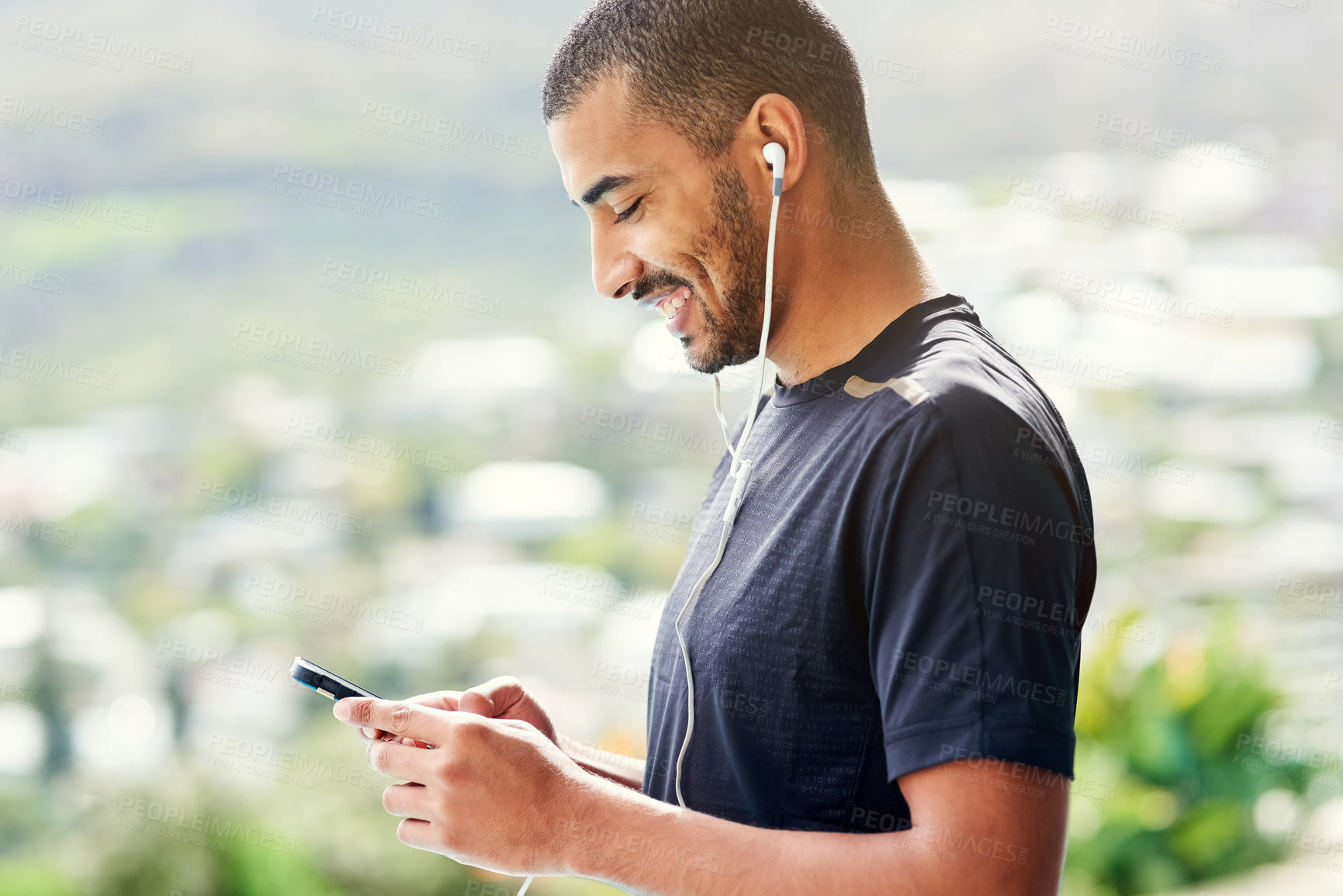 Buy stock photo Cropped shot of a young sporty man checking his playlist before a run