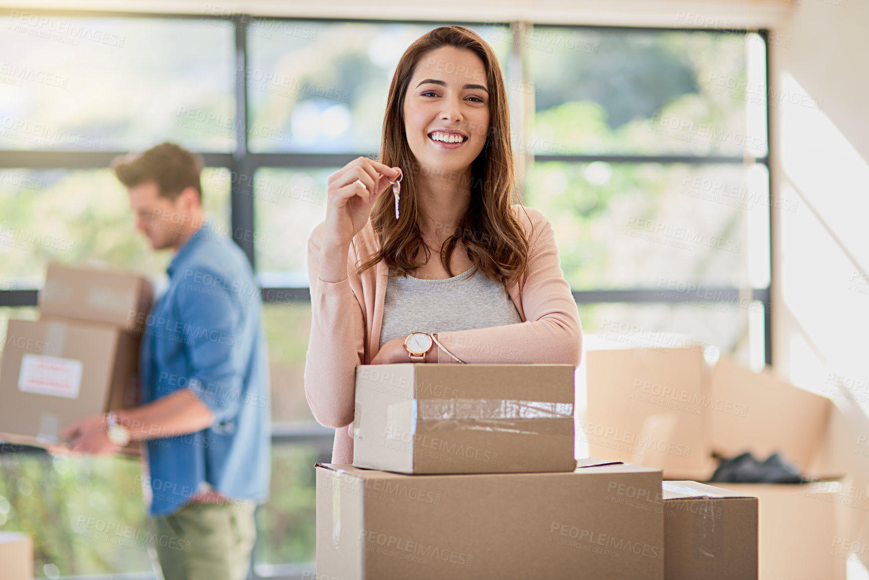 Buy stock photo Portrait of a young woman holding up the keys to a new home with her boyfriend in the background