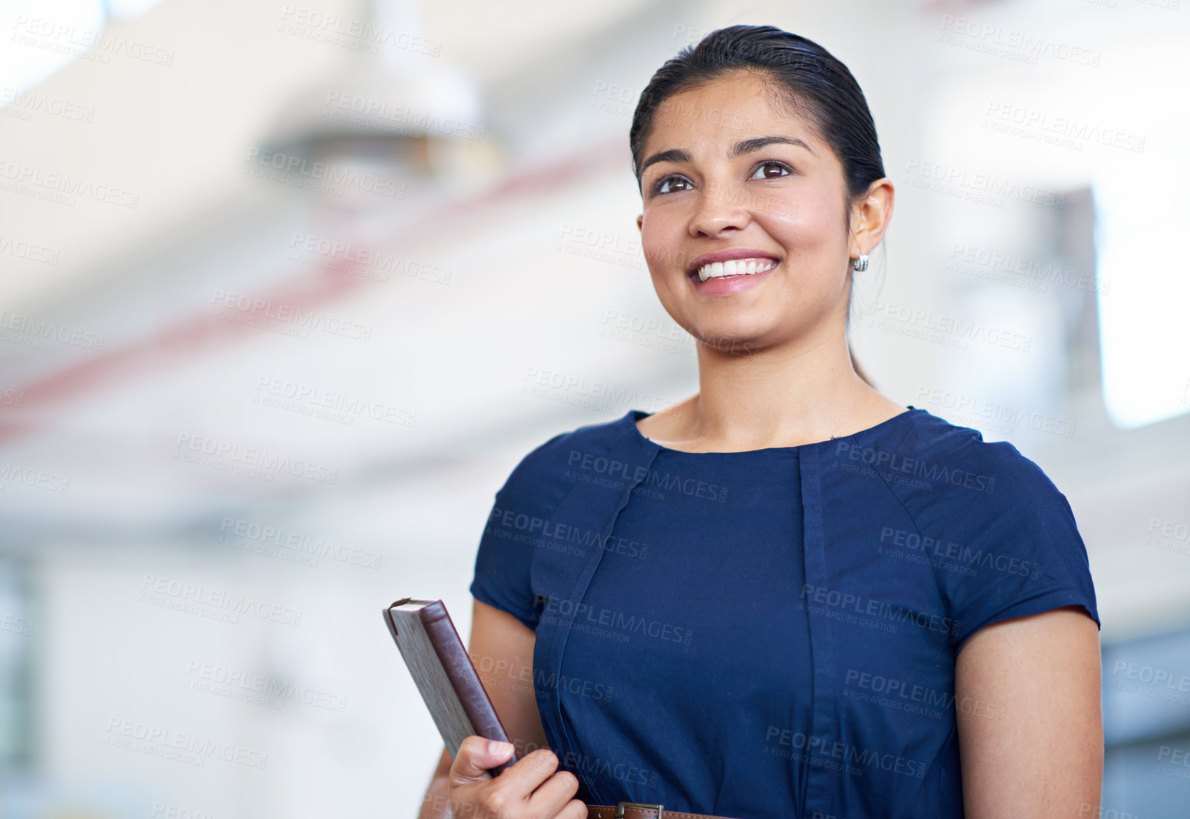 Buy stock photo Shot of an attractive young businesswoman holding her journal while standing in an office