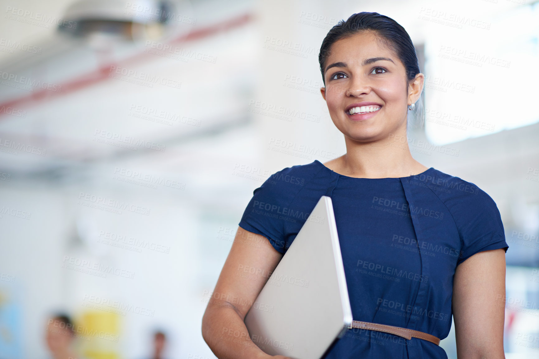 Buy stock photo Shot of an attractive young businesswoman carrying a laptop in the office