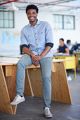 Buy stock photo Full lenght portrait of a handsome young businessman sitting on a desk in his office