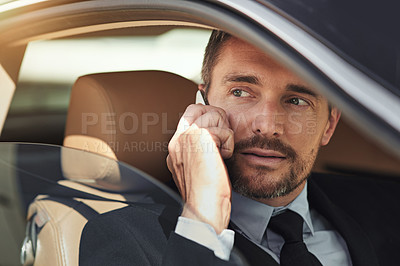 Buy stock photo Shot of a businessman using his phone while driving a car