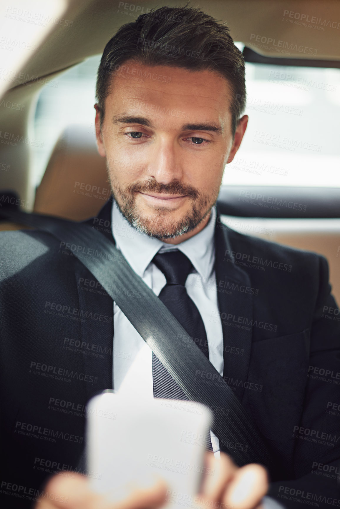 Buy stock photo Shot of a businessman using his phone while traveling in a car