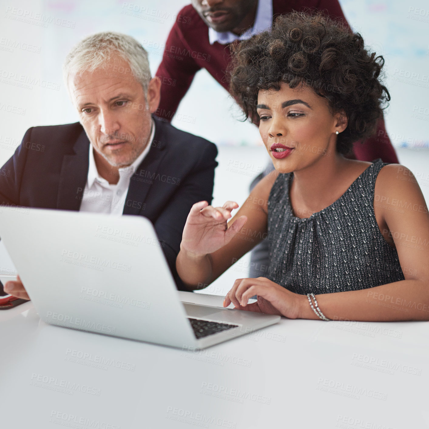 Buy stock photo Cropped shot of a group of businesspeople discussing something on a laptop