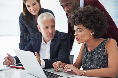 Buy stock photo Cropped shot of a group of businesspeople discussing something on a laptop