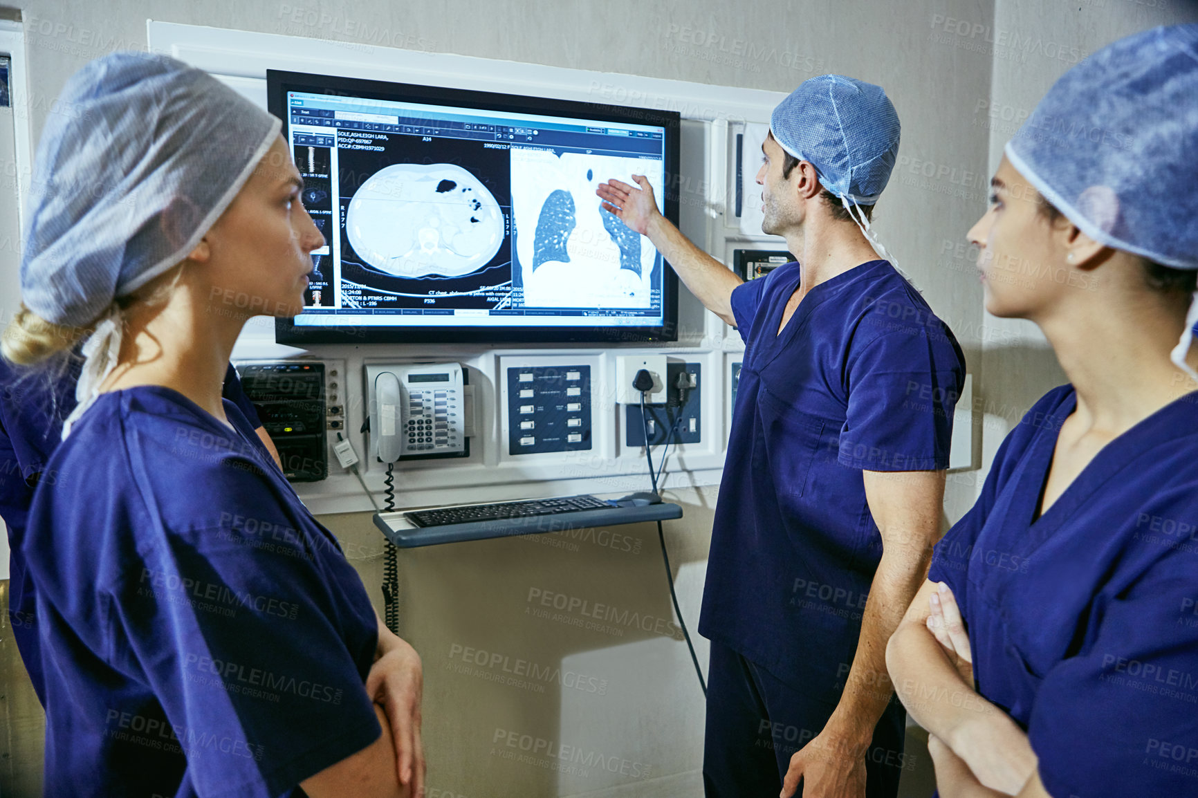 Buy stock photo Shot of a team of surgeons discussing a patient’s medical scans