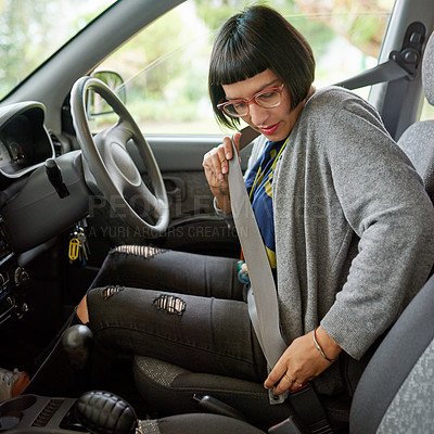 Buy stock photo Shot of a young woman buckling up her seat belt before going for a drive