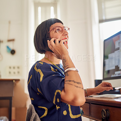 Buy stock photo Shot of a stylish young designer talking on the phone while working on computer in her studio