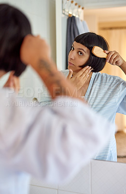 Buy stock photo Shot of a young woman in a bathrobe brushing her hair in her bathroom mirror in the morning