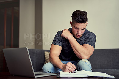 Buy stock photo Shot of a driven young man using his laptop to work from home