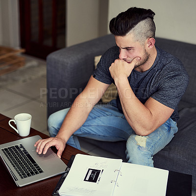 Buy stock photo Shot of a driven young man using his laptop to work from home