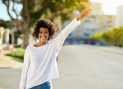 Buy stock photo Portrait of a happy young woman gesturing to catch a cab in the city
