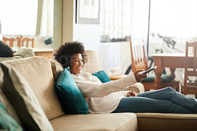 Buy stock photo Shot of a young woman relaxing on the sofa at home and watching tv