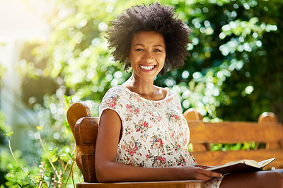 Buy stock photo Shot of a young woman relaxing with a book outdoors