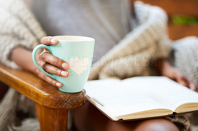 Buy stock photo Cropped shot of a woman relaxing with a book and a cup of coffee