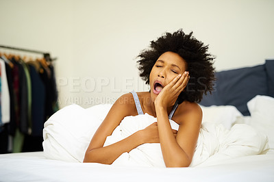 Buy stock photo Shot of a tired young woman yawning in bed at home
