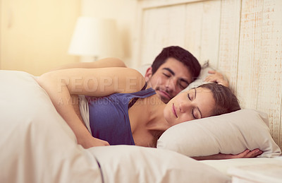 Buy stock photo Shot of a loving young couple sleeping in bed together
