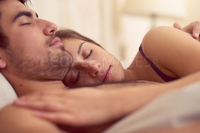 Buy stock photo Shot of a loving young couple sleeping in bed together