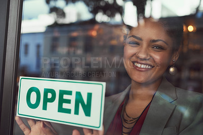 Buy stock photo Portrait of a young business owner hanging up an 