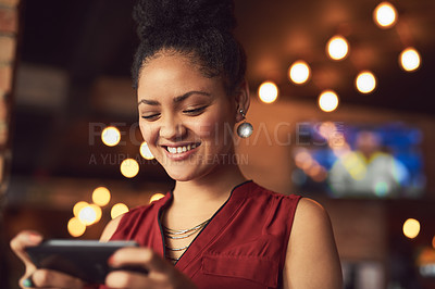 Buy stock photo Cropped shot of a young woman texting on a cellphone in a cafe